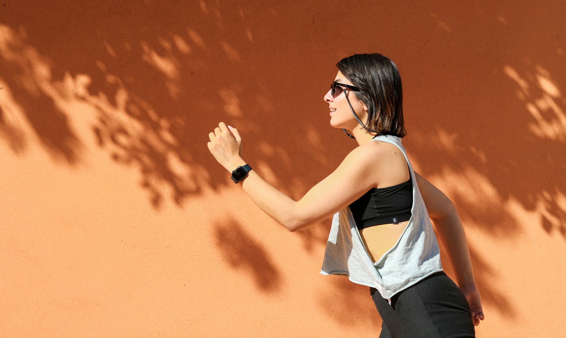 Woman running training session outdoors against a sunlit terracotta wall